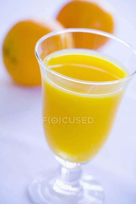 Склянка апельсинового соку та апельсинів — стокове фото
