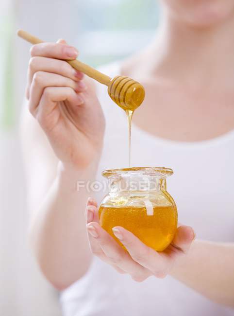 Woman holding jar of honey — Stock Photo