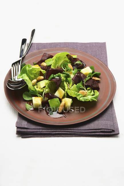 Крупный план салата с фруктами и кедровыми орехами на тарелке — стоковое фото