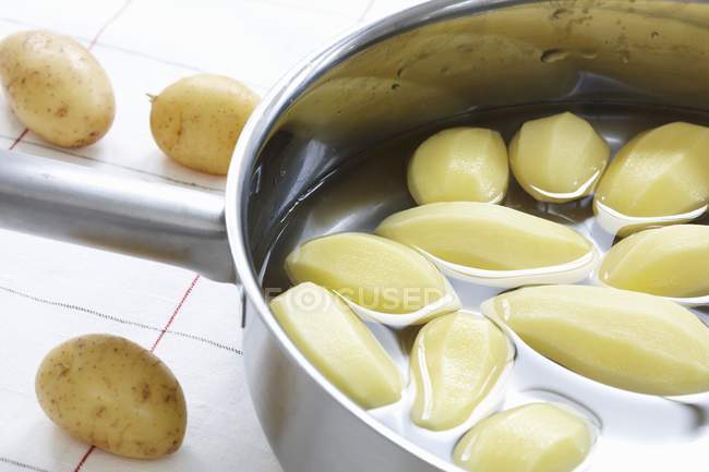 Пательня очищеної картоплі у воді — стокове фото