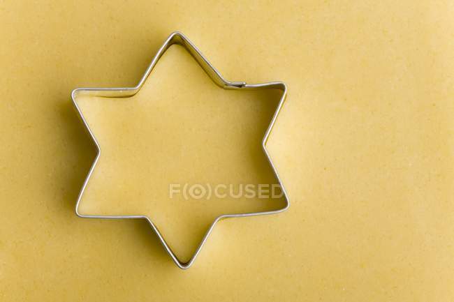 Nahaufnahme einer sternförmigen Ausstechform auf gelbem Teig — Stockfoto