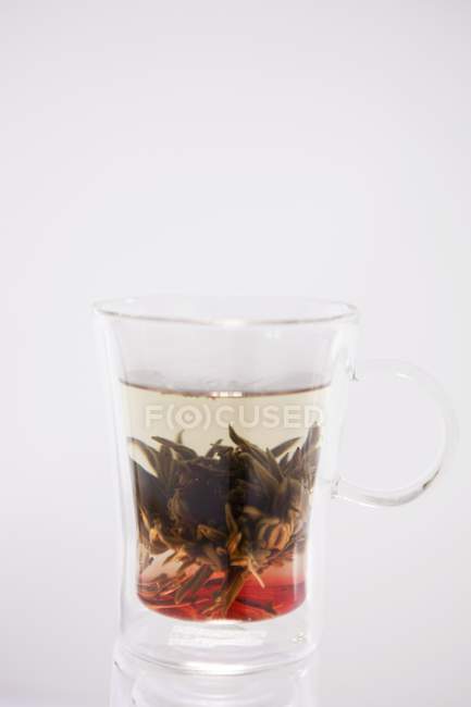 Чай с цветком чая в стеклянном кувшине — стоковое фото