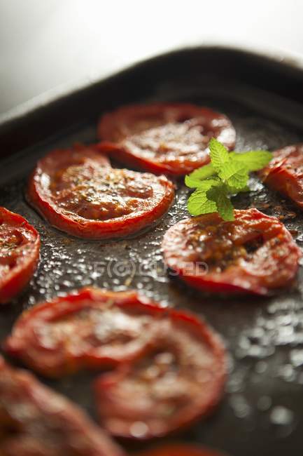 Roasted tomato on black baking tray — Stock Photo