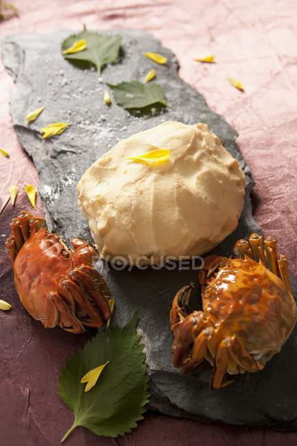 Closeup view of grilled basil crabs with dough, leaves and petals on schist board — Stock Photo