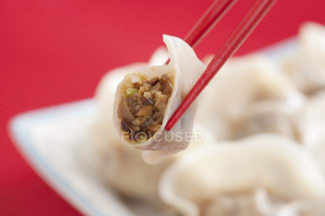 Closeup view of dumplings between red chopsticks — Stock Photo