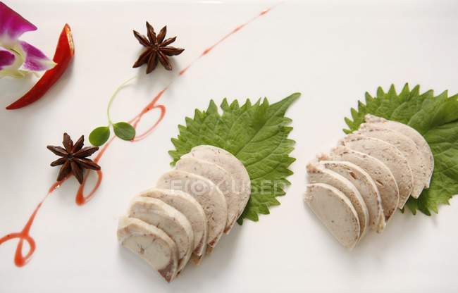 Vue du dessus du pâté de foie de canard tranché avec anis étoilé, feuilles et sauce — Photo de stock