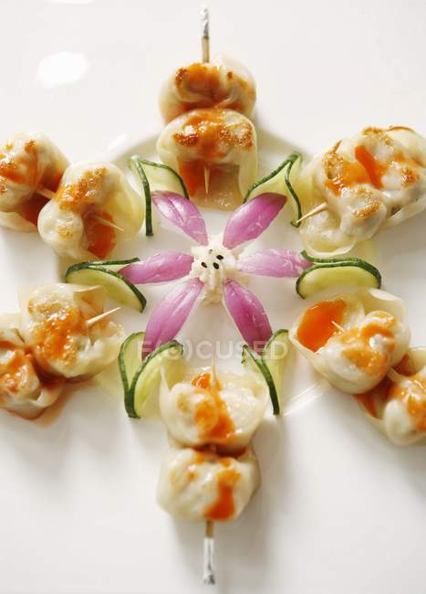 Nahaufnahme von gebratenen Knödel in Sauce mit Gemüse in Blütenform angeordnet — Stockfoto