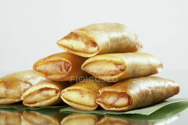 Closeup view of piled spring rolls on leaves — Stock Photo