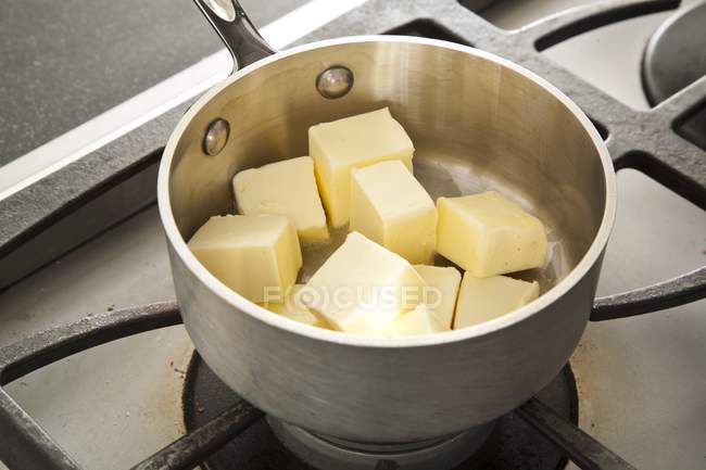 Vista de perto de cubos de manteiga em uma panela no fogão — Fotografia de Stock