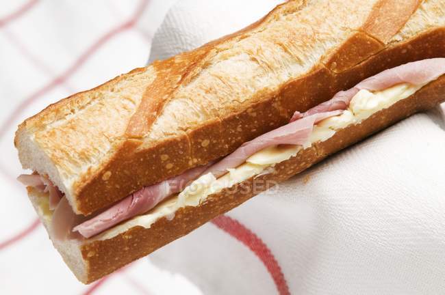 Ham baguette on towel — Stock Photo