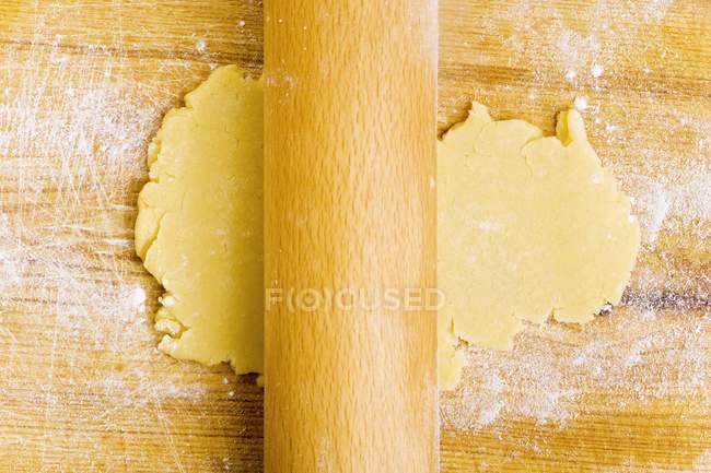 Vue rapprochée du dessus du déploiement de la pâte à biscuits avec rouleau à pâtisserie — Photo de stock