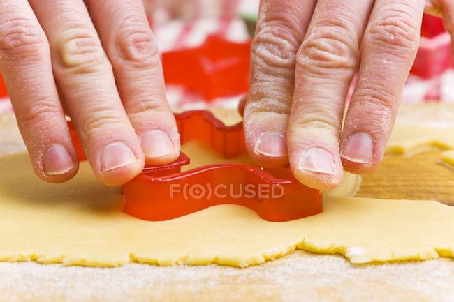 Vista close-up de mãos cortando biscoito com cortador — Fotografia de Stock