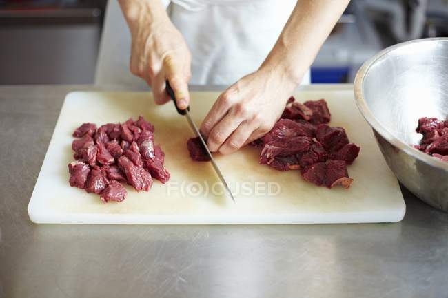 Chef cutting raw beef — Stock Photo