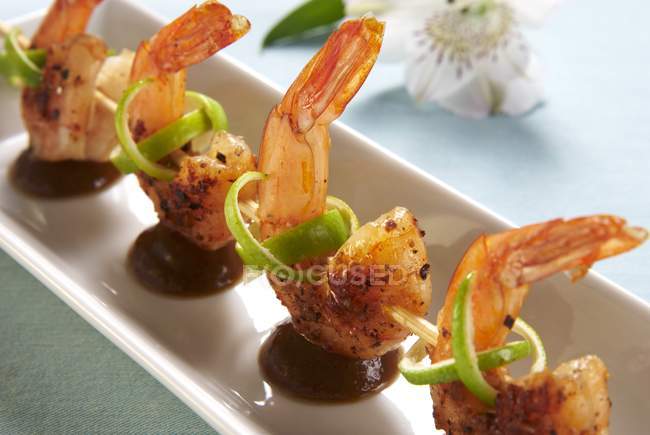 Closeup view of fried prawn kebabs with limes and a tamarind sauce — Stock Photo