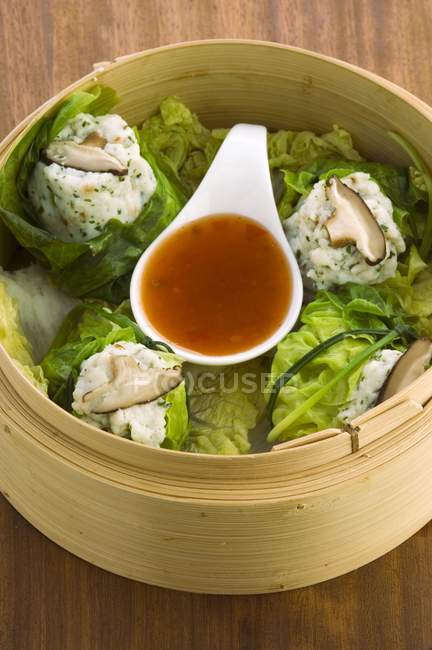 Elevated view of steamed fish dumplings with sauce in bamboo basket — Stock Photo