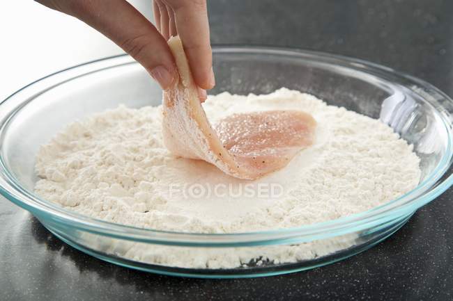 Female hand Dredging Chicken in Flour — Stock Photo