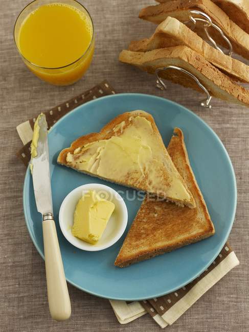 Toast triangles with butter and orange juice — Stock Photo