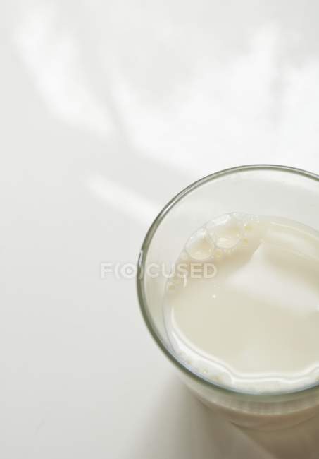 Verre de lait sur surface blanche — Photo de stock