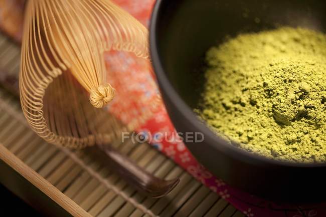 Vista de cerca del polvo de té verde Matcha japonés en un cuenco negro ceremonial Matcha con batidor - foto de stock