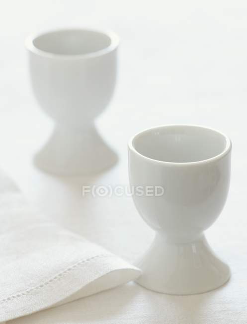 Vista de cerca de dos tazas de huevo blanco con una servilleta - foto de stock