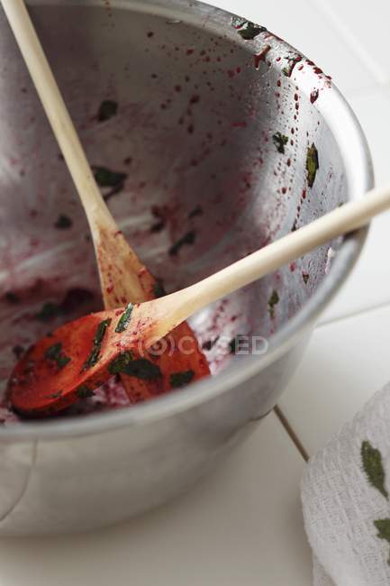 Closeup view of metal bowl and wooden spoons with salad remains — Stock Photo