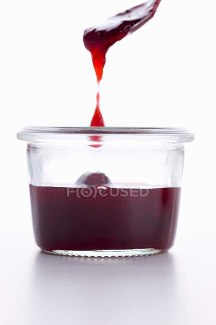 Jam dripping from spoon into jar — Stock Photo