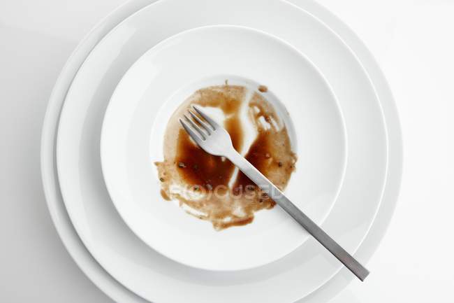 Blick von oben auf die Reste einer Sauce und einer Gabel auf einem Teller — Stockfoto
