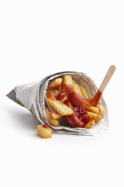 Potato fries with ketchup wrapped in newspaper — Stock Photo