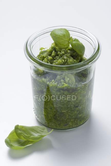 Closeup view of green Pesto with leaves in a jar — Stock Photo