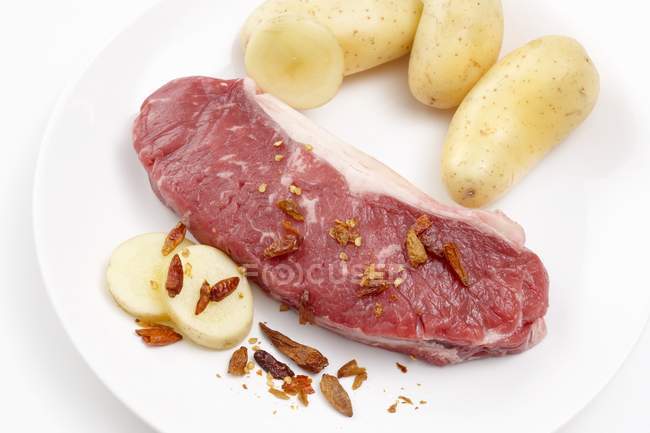 Carne crua com batatas e especiarias — Fotografia de Stock