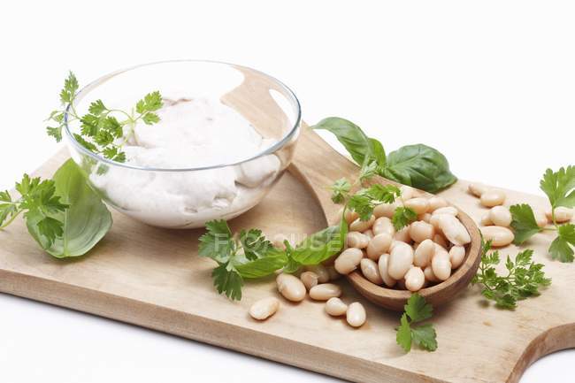 White beans, fresh herbs and cream on wooden desk on white background — Stock Photo