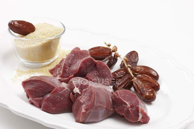 Closeup view of venison meat with dates and grains in glass bowl — Stock Photo