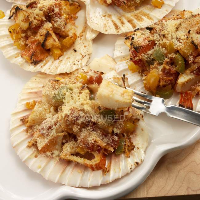 Conchas de vieira brasileña rellenas de cangrejo y coco en plato blanco con tenedor - foto de stock