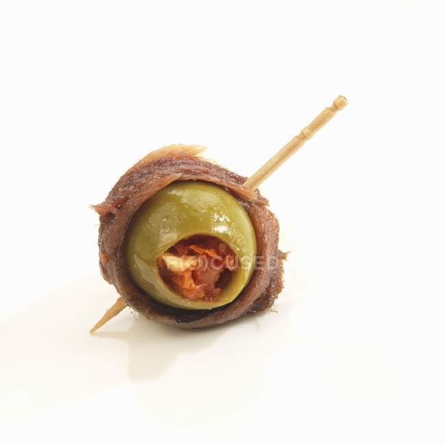 Olive farci enveloppé dans l'anchois avec un cure-dent sur la surface blanche — Photo de stock