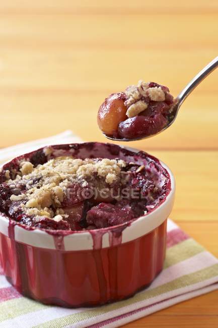 Closeup view of cherry cobbler pie in bowl and on spoon — Stock Photo
