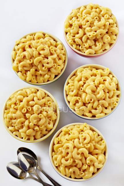 Bowls of macaroni and cheese and spoons — Stock Photo