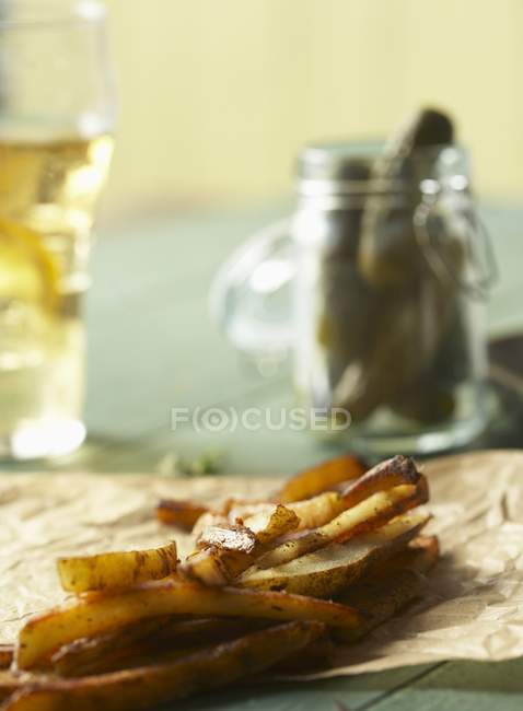 Fries on Parchment Paper; Jar of Pickles and Glass of Beer — Stock Photo