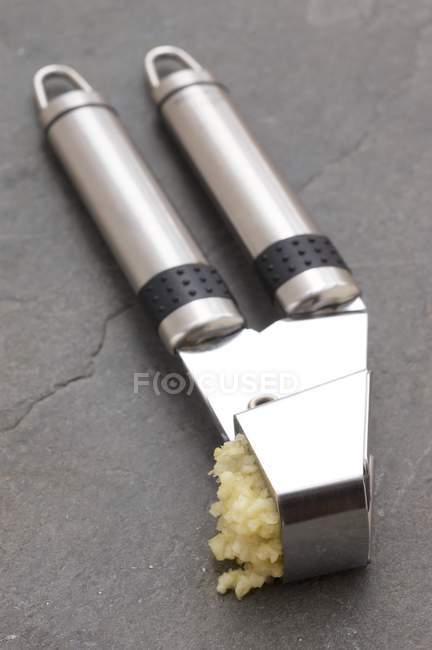 Um dente de alho esmagado em uma prensa de alho — Fotografia de Stock