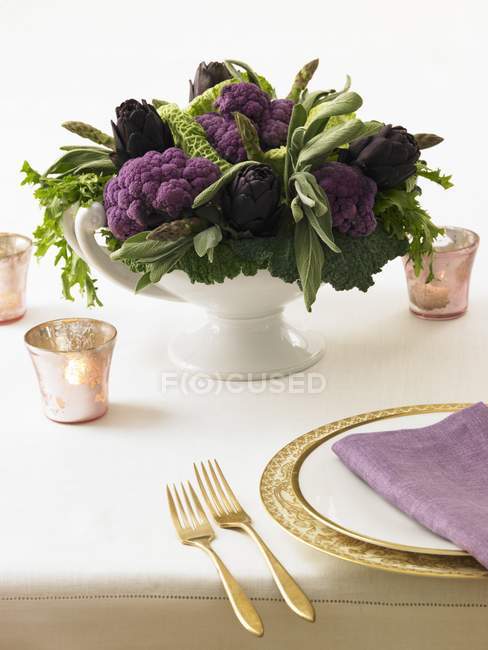 Крупный план накрытого стола с фиолетовыми артишоками и цветной капустой — стоковое фото