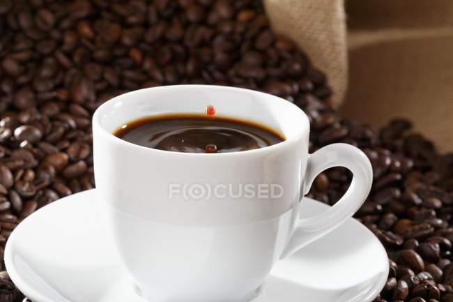 Drops of coffee falling into cup — Stock Photo