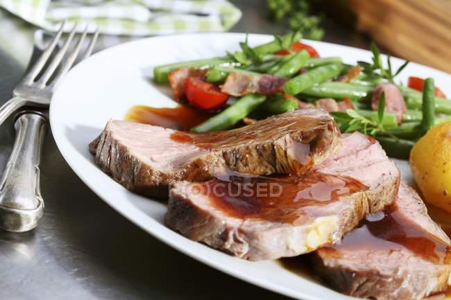 Roasted beef with gravy and beans — Stock Photo