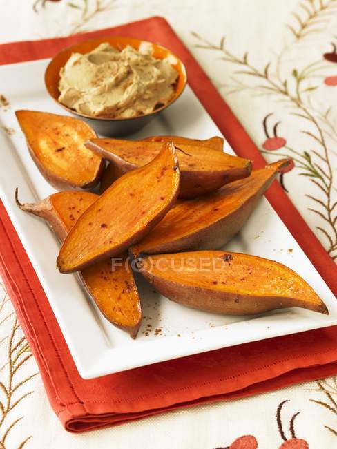 Gebratene Süßkartoffeln mit Zimtbutter auf weißem Teller über rotem Handtuch — Stockfoto