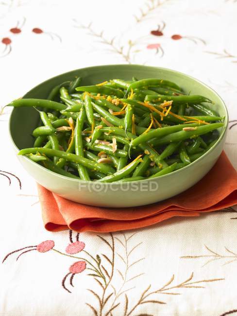 Grüne Bohnen mit Orangenschale im Teller über dem Handtuch — Stockfoto