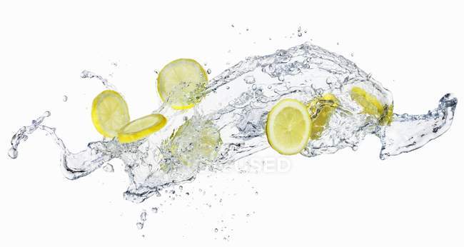 Rodajas de limón en salpicaduras de agua - foto de stock