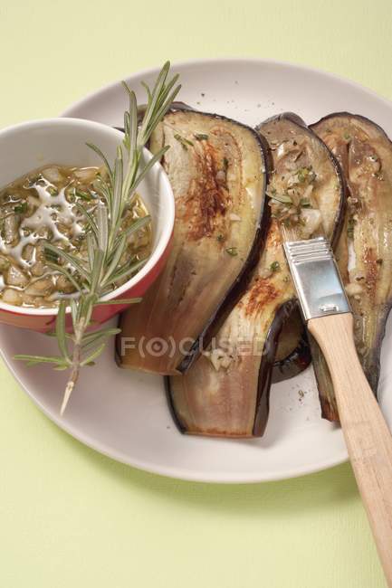 Grilled aubergines with a herb marinade on white plate  with whisk — Stock Photo
