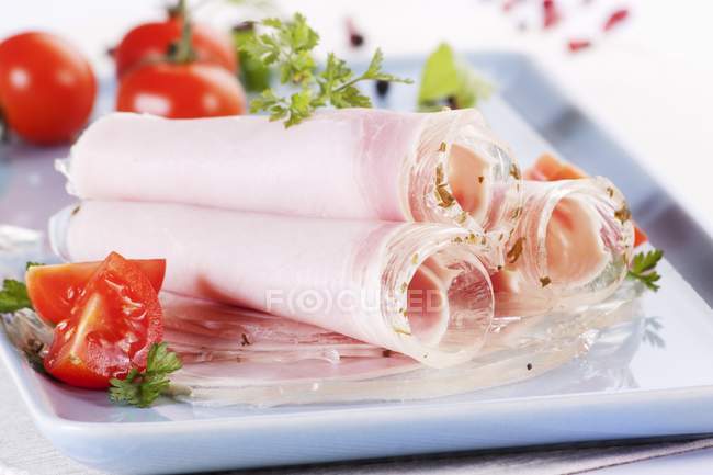 Rolls of ham in aspic with tomatoes — Stock Photo