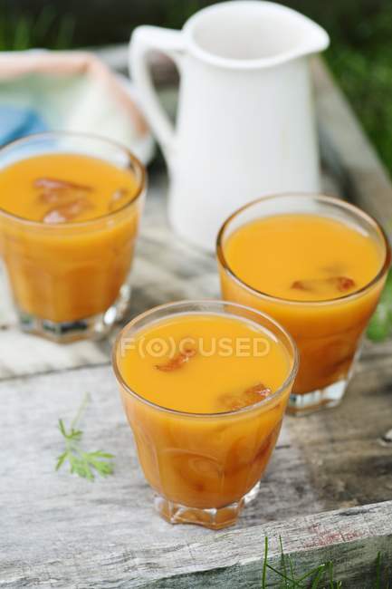 Sumo de maçã, laranja e cenoura servido em copos — Fotografia de Stock