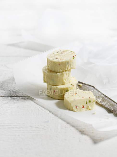 Vista close-up de chili e pedaços de manteiga de limão com faca no papel — Fotografia de Stock