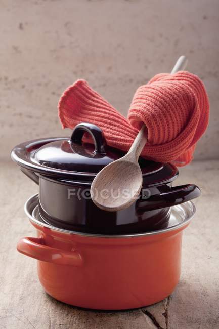 Closeup view of pots with a wooden spoon and pot holders — Stock Photo
