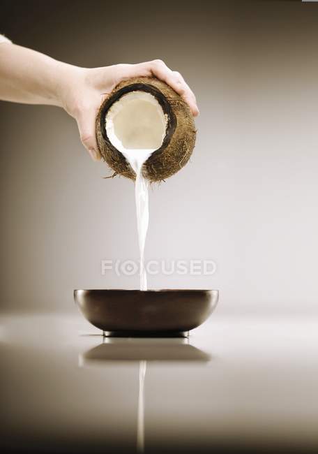 Hand Pouring Milk Out of Coconut — Stock Photo